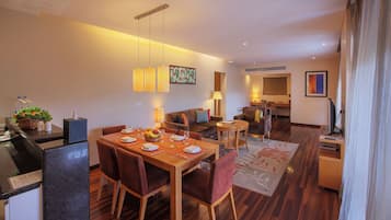 A modern hotel room with a dining area, a living area, and a kitchenette.
