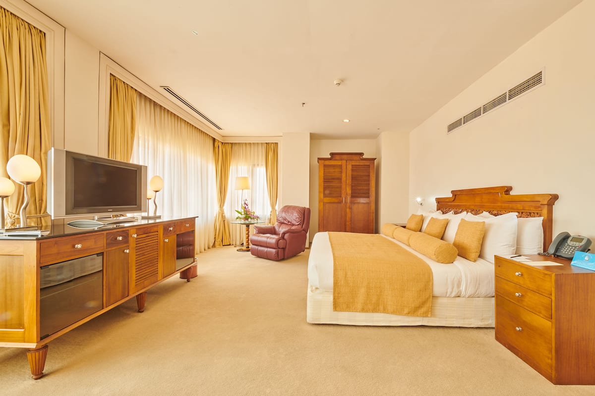 A hotel room with a bed, a television, a desk, and a wardrobe.