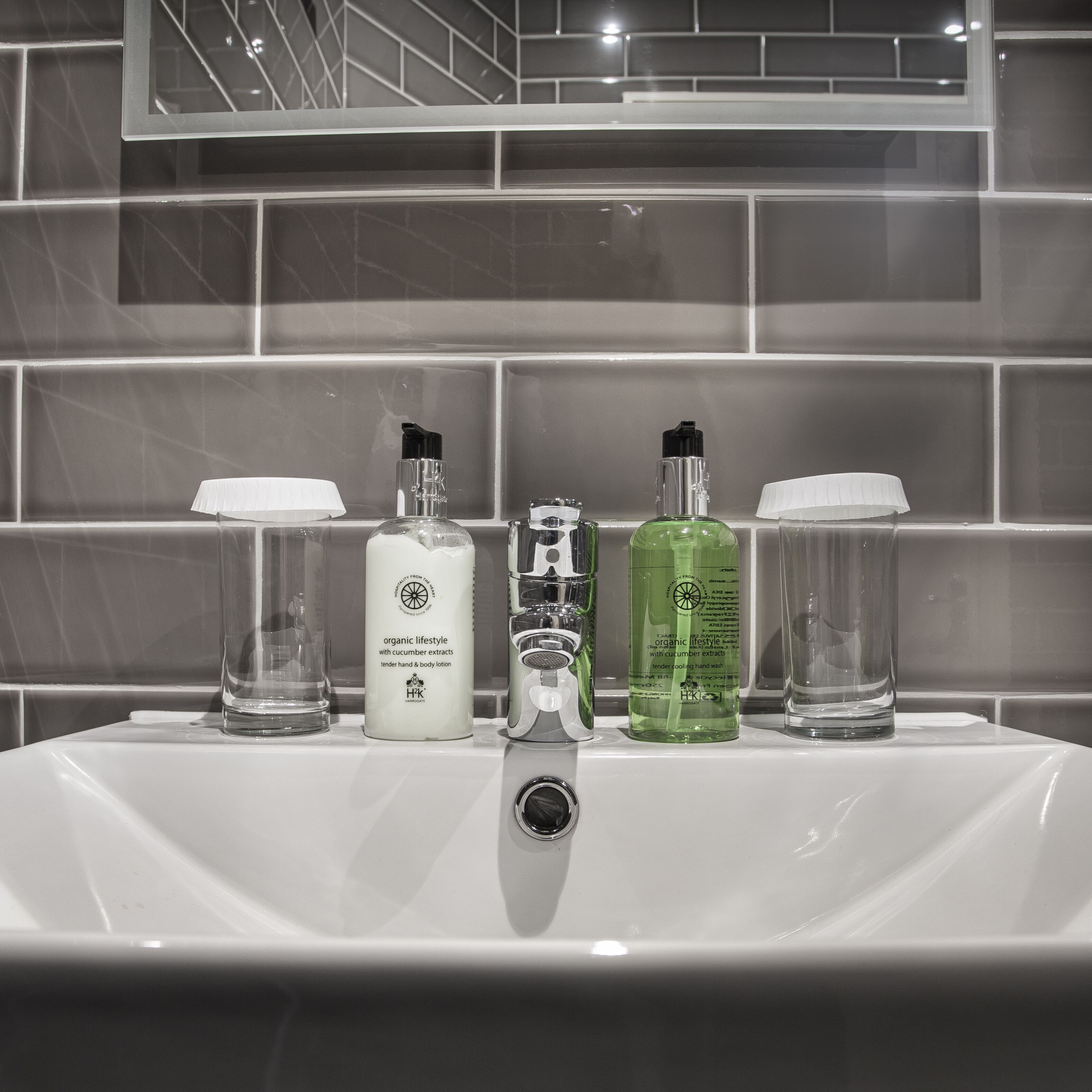 A bathroom sink with five bottles of personal care products.