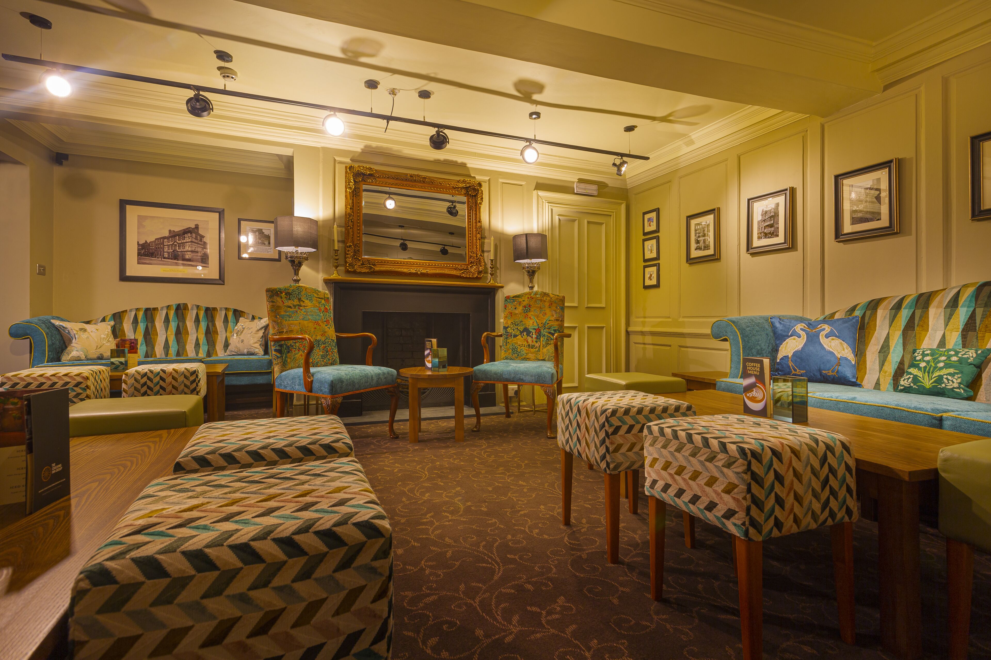 A hotel lobby with a fireplace, multiple seating areas, and framed pictures on the walls.