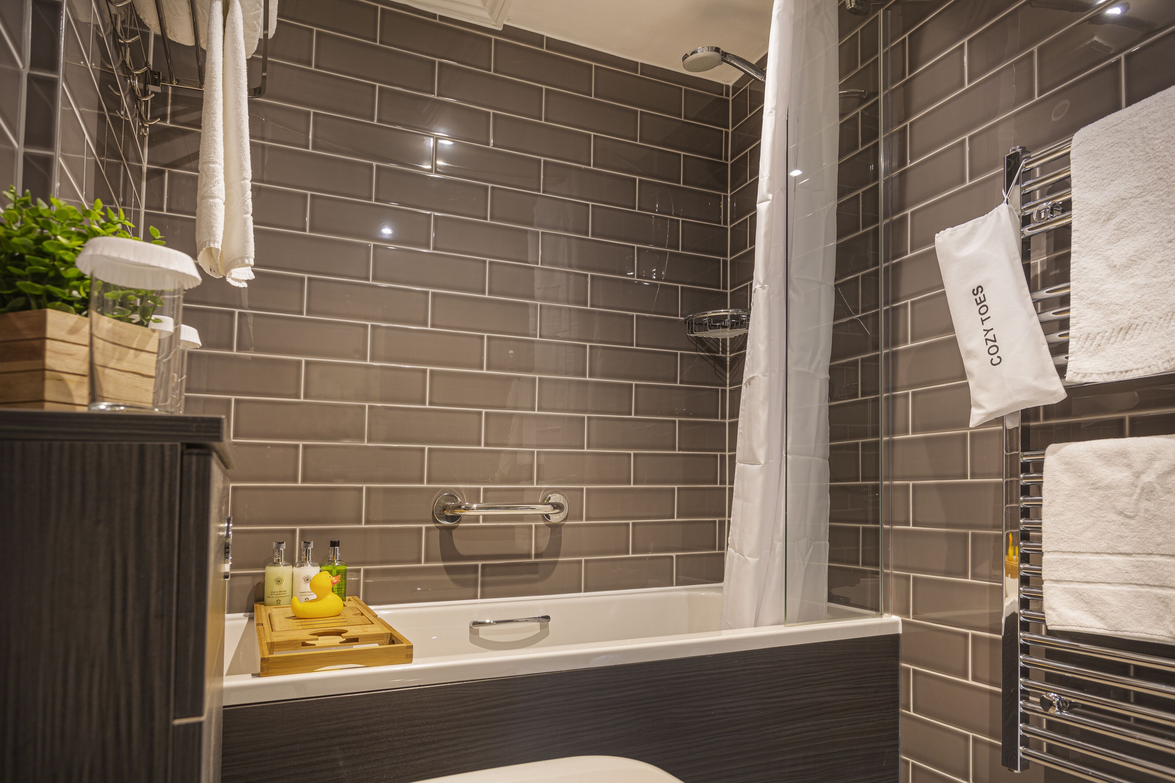 A modern bathroom with a bathtub, a shower, and a towel rack.