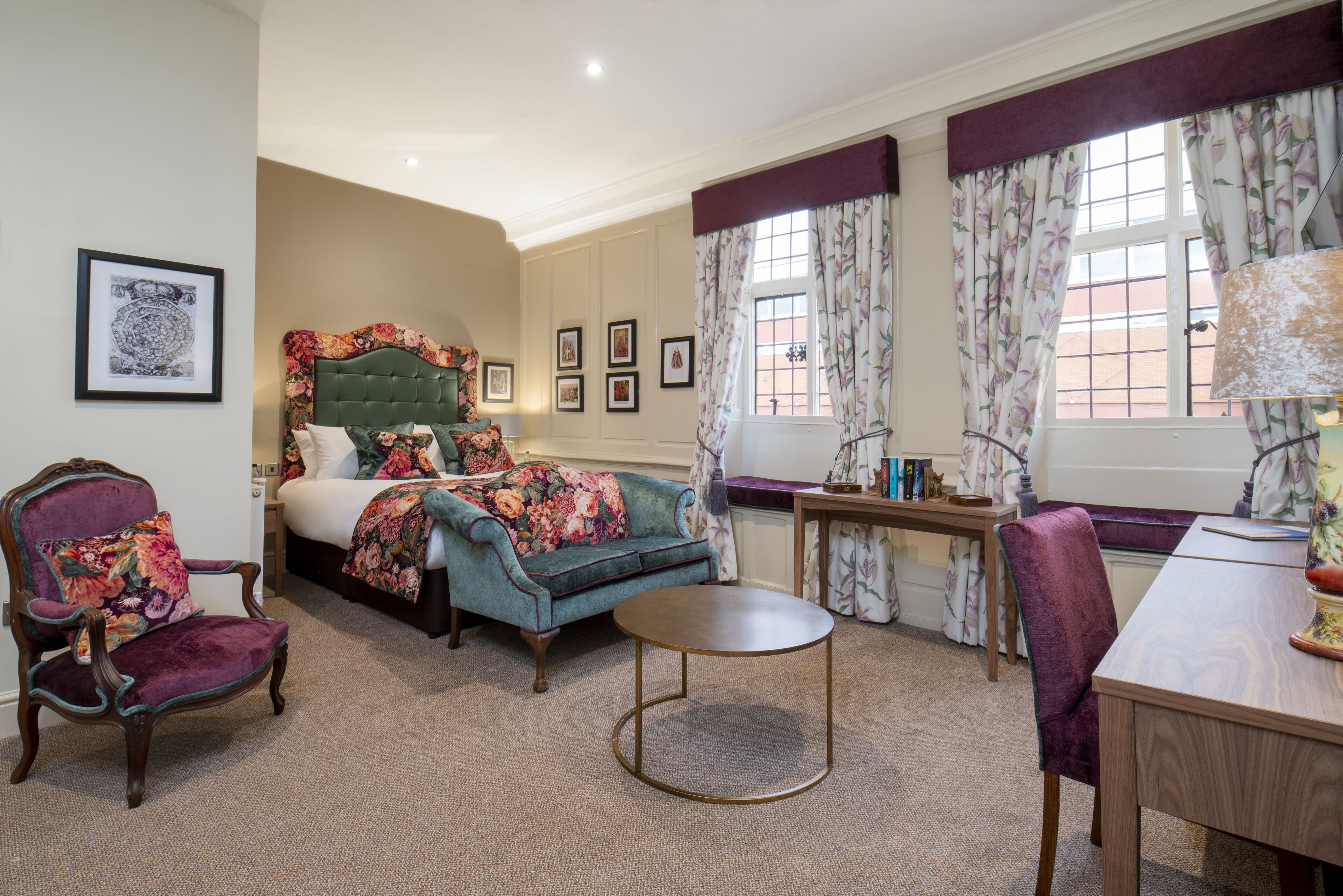 A bedroom with a large bed, a chair, a round table, and a desk.