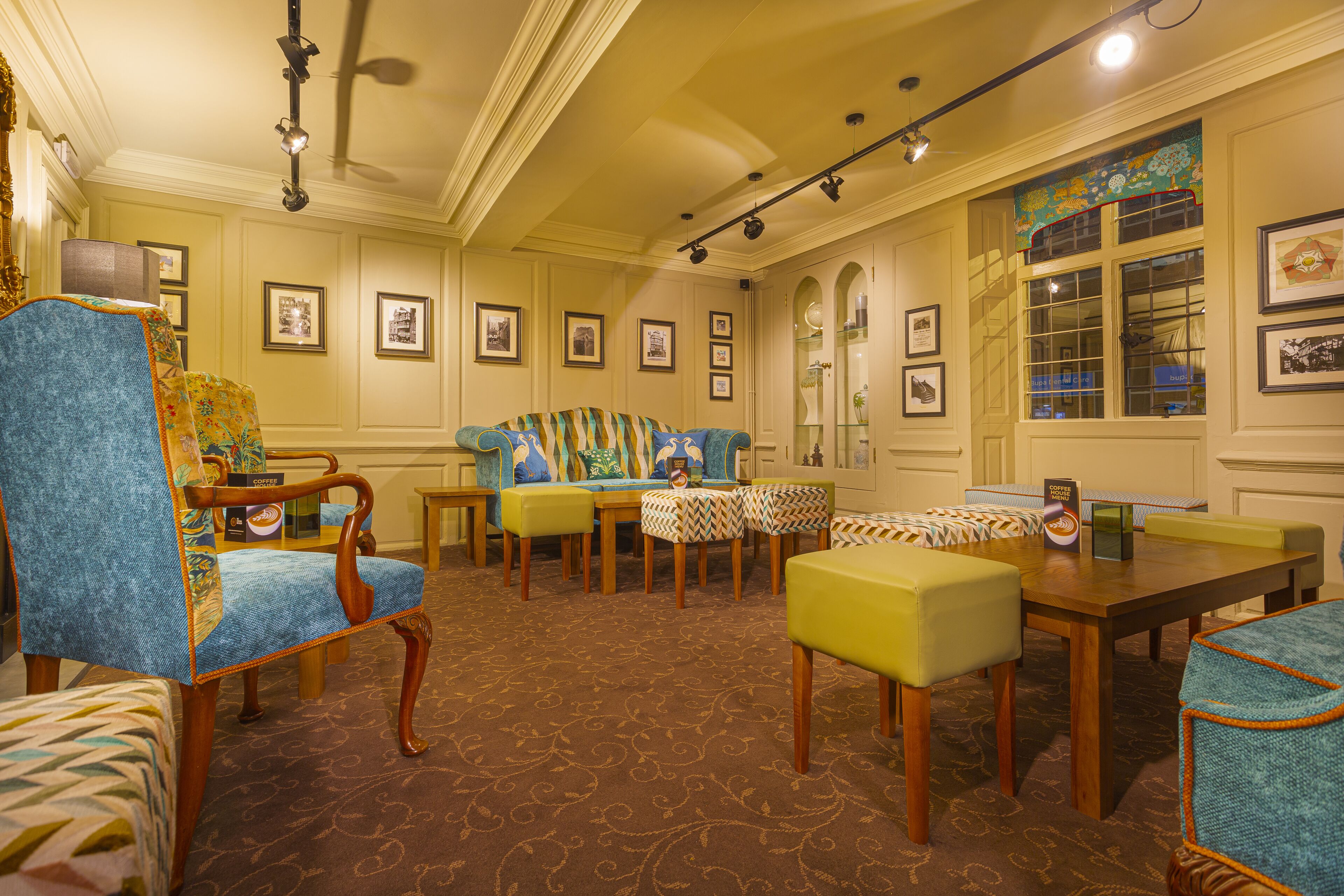 A room with a patterned carpet, a wooden coffee table, and a sofa with a patterned cushion.