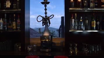 A bar with a hookah in the center, surrounded by shelves of liquor bottles.