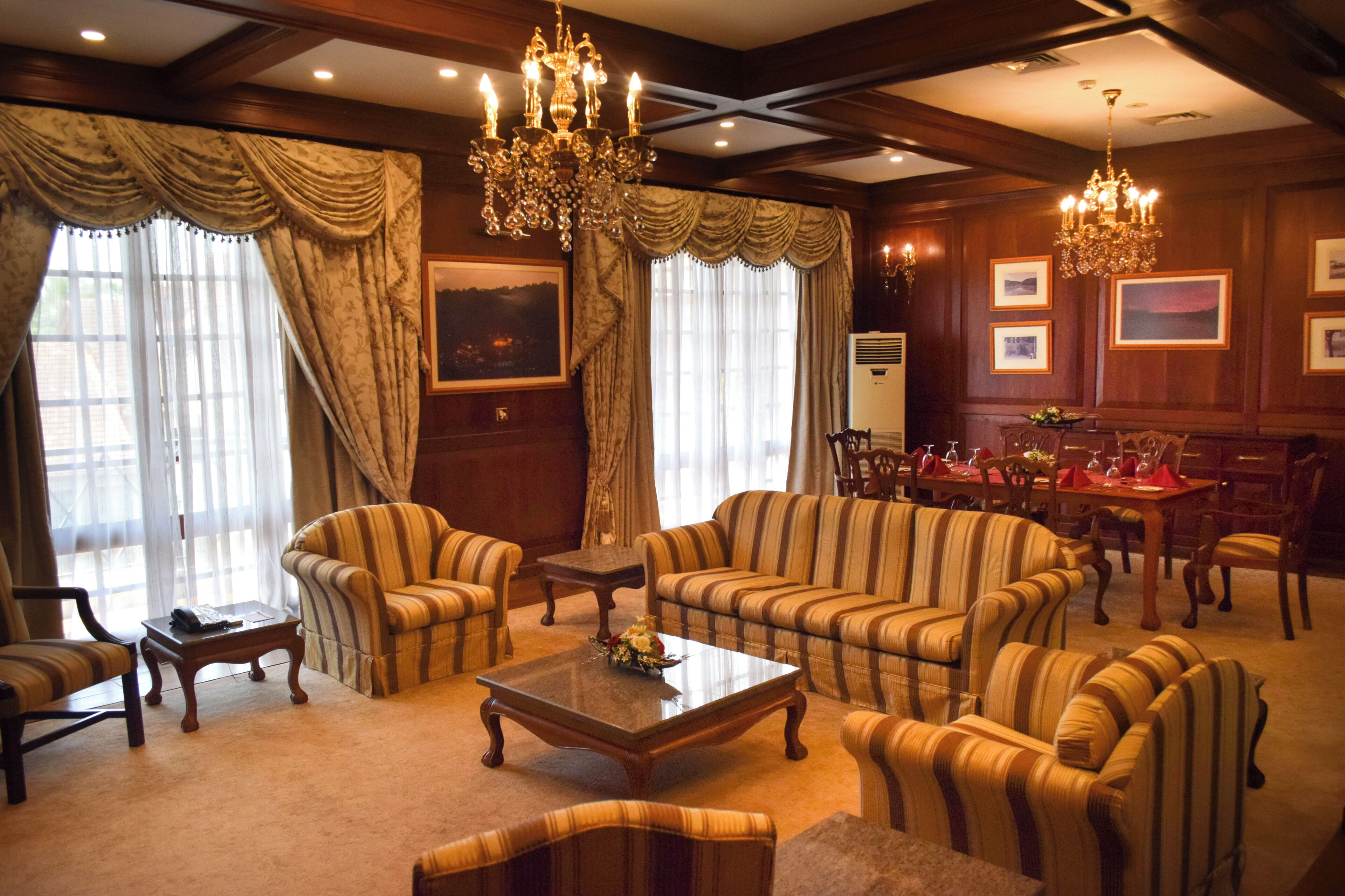 A spacious living room with striped sofas, a coffee table, and a chandelier.