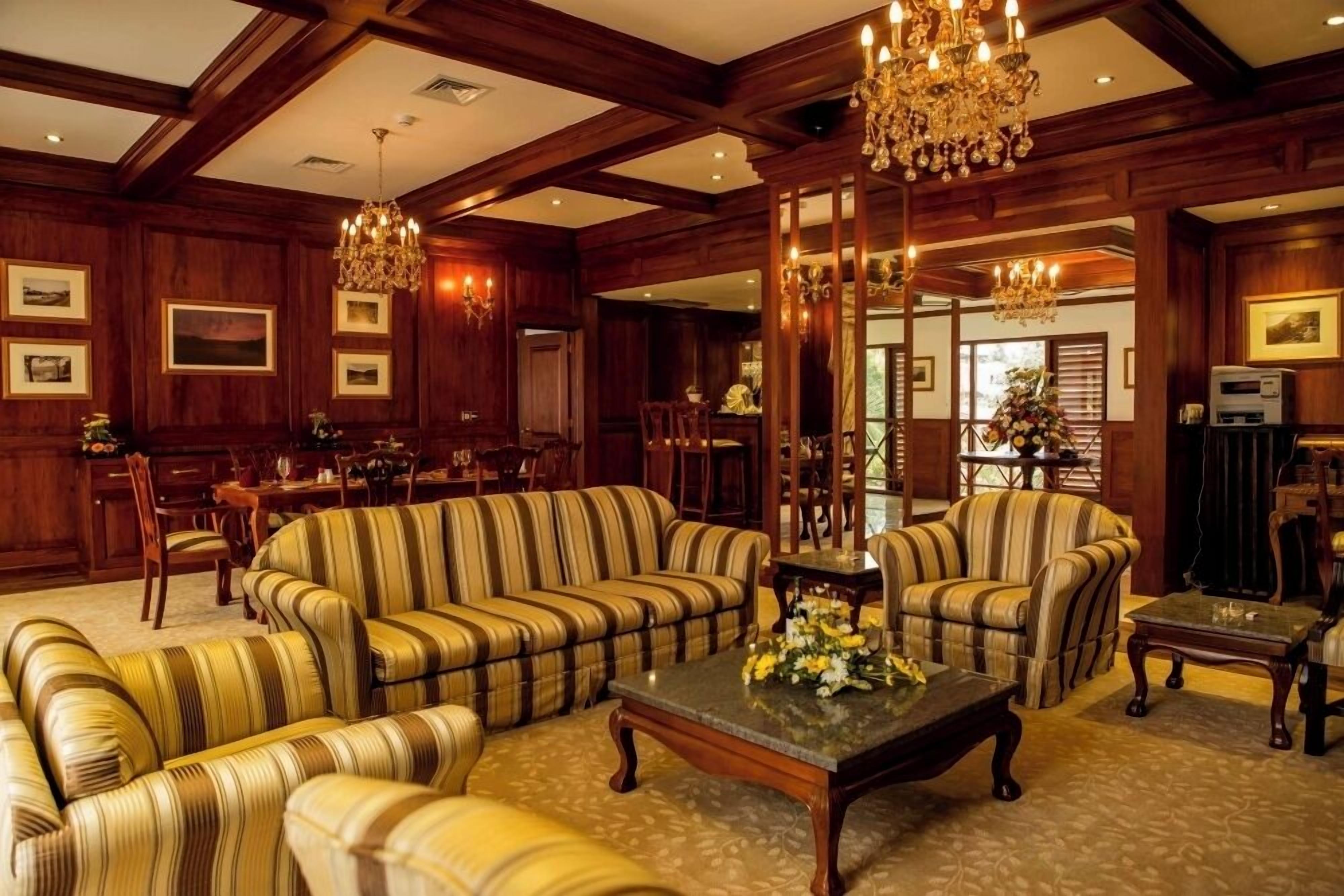 A spacious living room with striped sofas, a coffee table, and a chandelier.