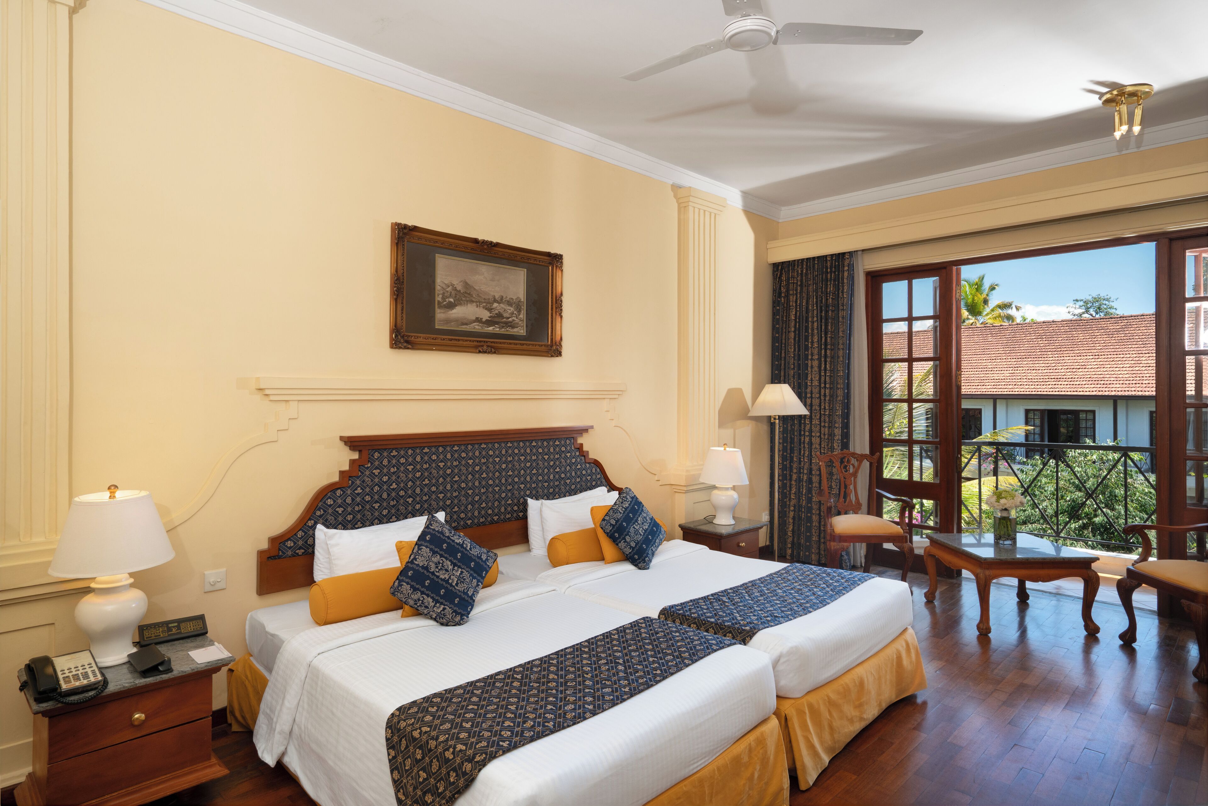 A hotel room with a large bed, two bedside tables, a ceiling fan, and a balcony with a view of the outside.