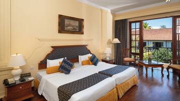 A hotel room with a large bed, two bedside tables, a ceiling fan, and a balcony with a view of the outside.