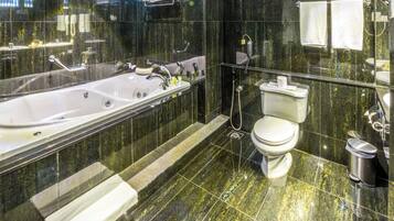 A modern bathroom with a large bathtub, toilet, and a glass-enclosed shower area.