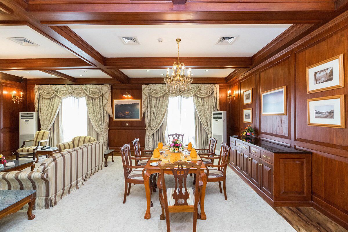 Un comedor formal con una mesa de madera dispuesta para seis personas, rodeada de sillas tapizadas.