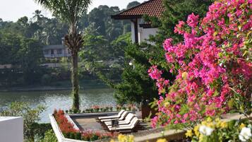 A pool area with lounge chairs and a view of a lake and buildings in the background.