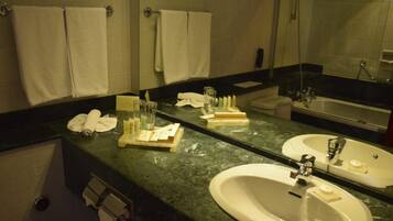 A bathroom with two sinks, a mirror, and towels hanging on the wall.