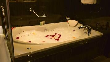 Una bañera llena de agua y pétalos de rosa dispuestos en forma de corazón.