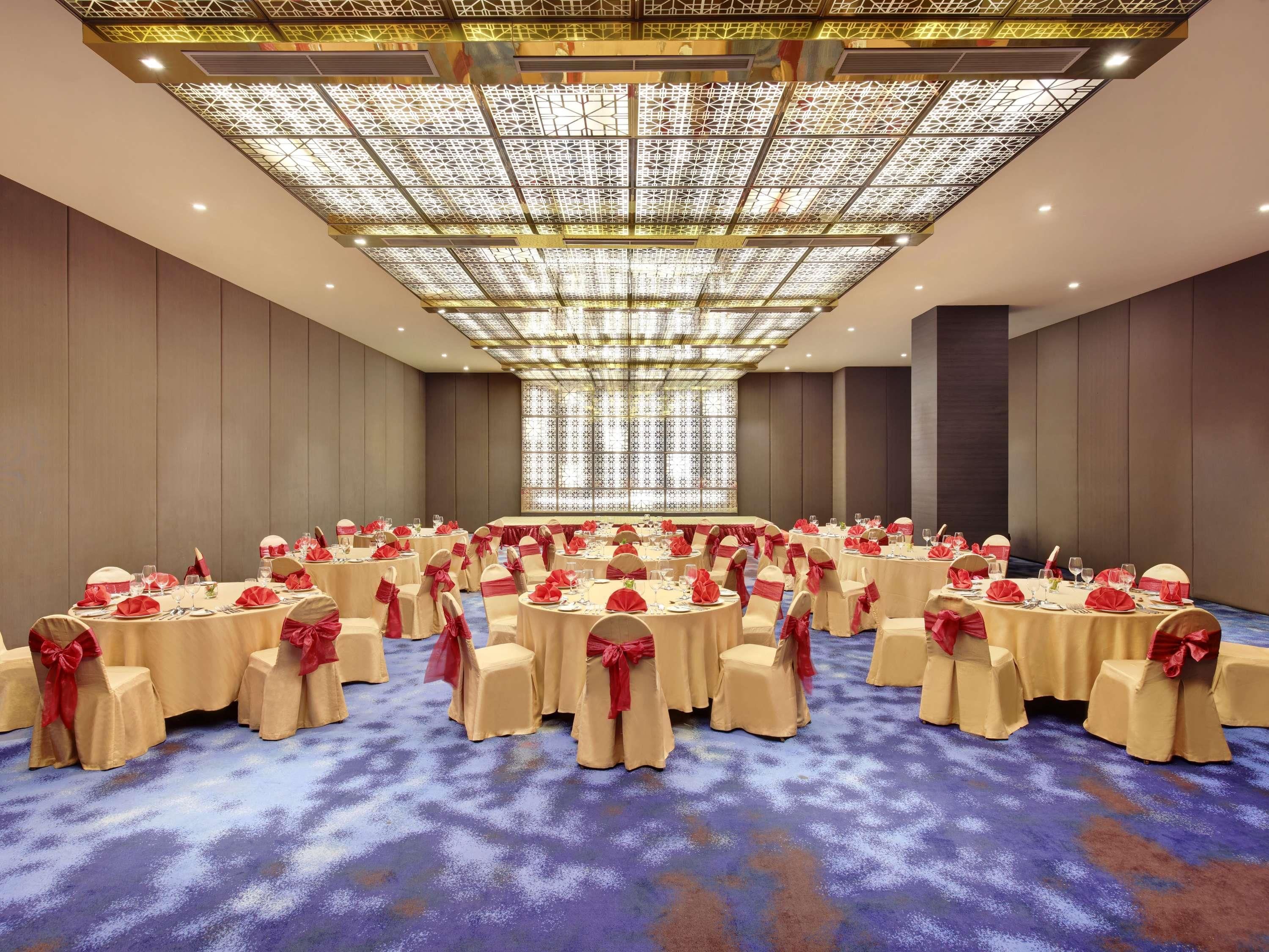 A conference room with round tables, chairs, and a patterned ceiling.