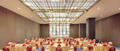 A conference room with round tables, chairs, and a patterned ceiling.