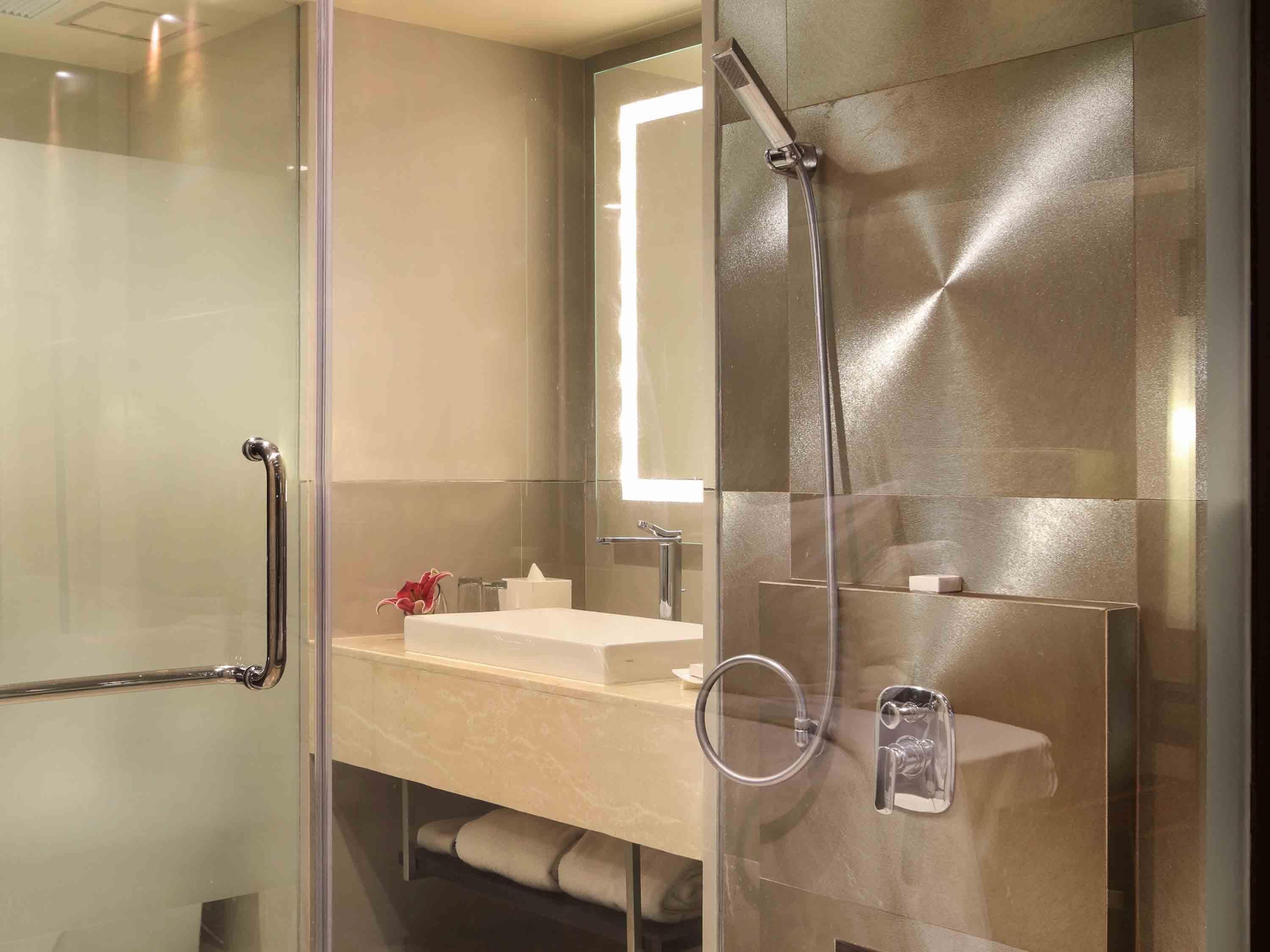 A modern bathroom with a glass partition, a sink, a mirror, and a shower.