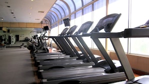 A row of treadmills in a gym with large windows and a high ceiling. - Grand Mercure Medan Angkasa (Medan)