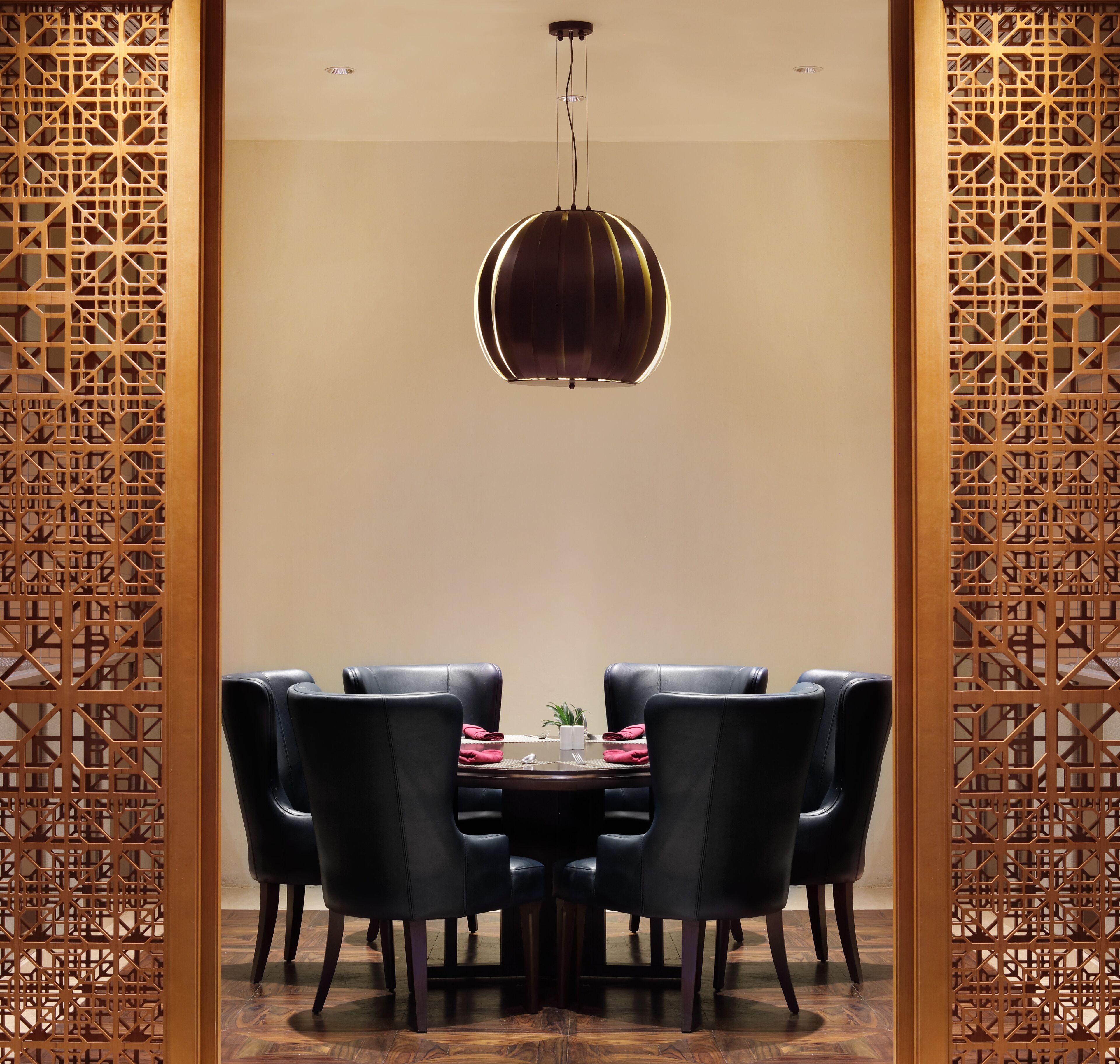 A dining area with a round table, black chairs, and a hanging light fixture.