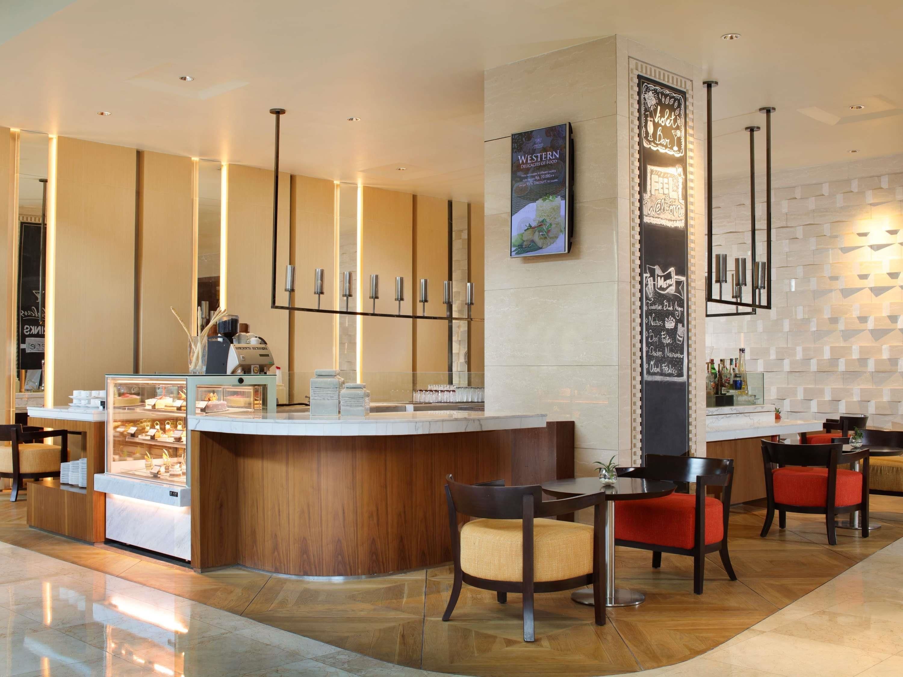 A modern hotel lobby with a reception desk, seating area, and a menu board.