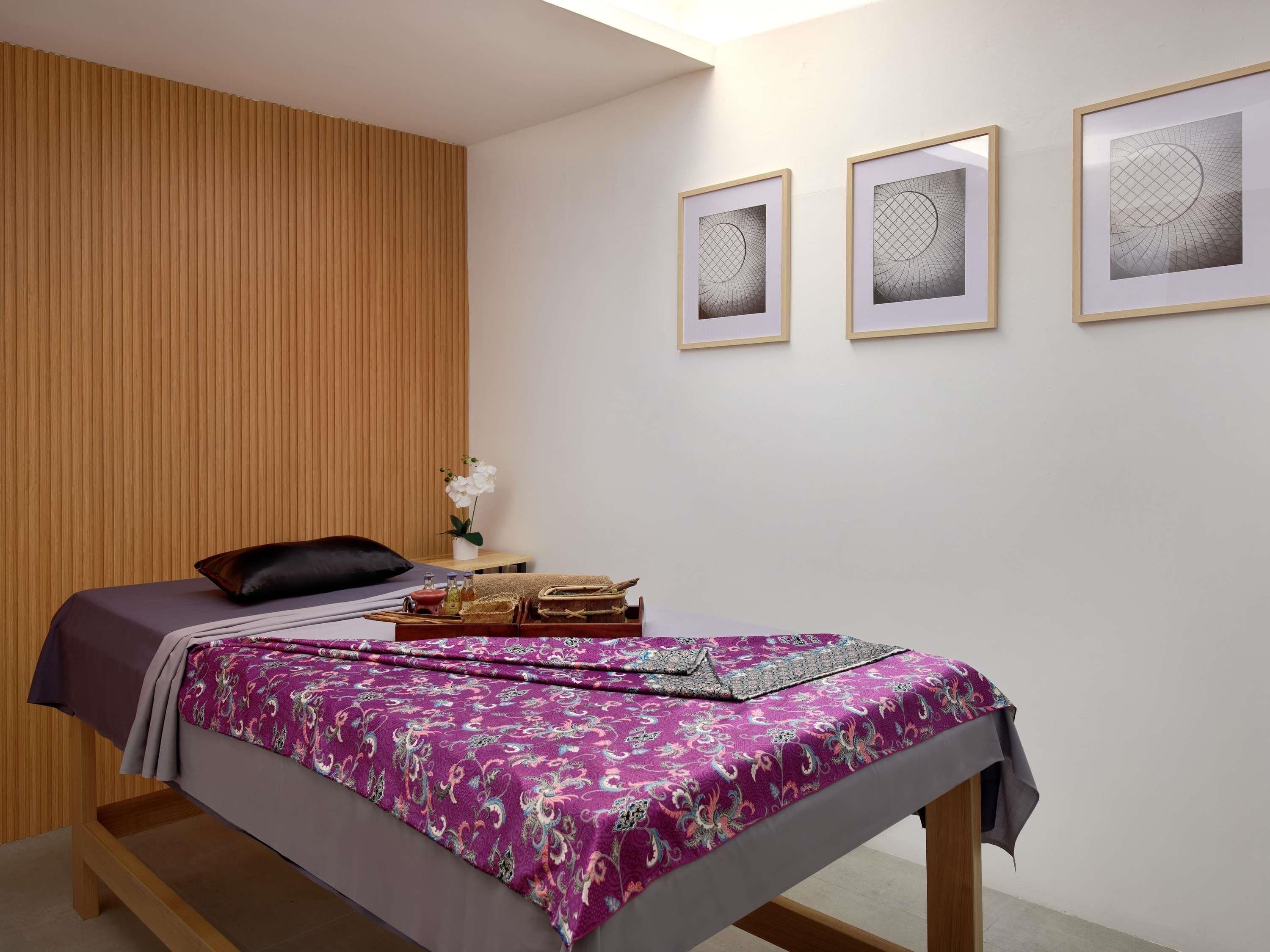 Een slaapkamer met een bed, een nachtkastje en drie ingelijste kunstwerken aan de muur.