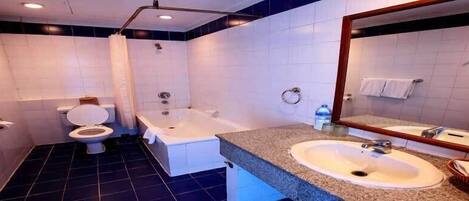 A modern bathroom with a toilet, bathtub, and two sinks.