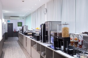 Una moderna cucina d'hotel con postazioni self-service per caffè, yogurt e cereali.