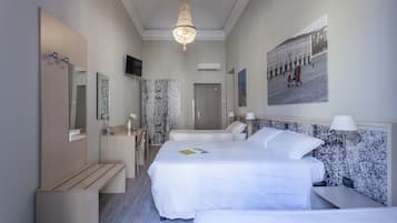 Habitación cuádruple | Edredón, minibar, caja de seguridad en la habitación y escritorio