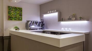Una cucina moderna con macchina da caffè espresso integrata, una parete verde con piante e un design minimalista.