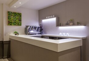 A modern kitchen with a built-in espresso machine, a large green plant wall, and a minimalist design.