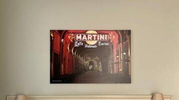 A hotel room with a bed, two bedside tables, and a wall-mounted picture of a red-lit street scene.