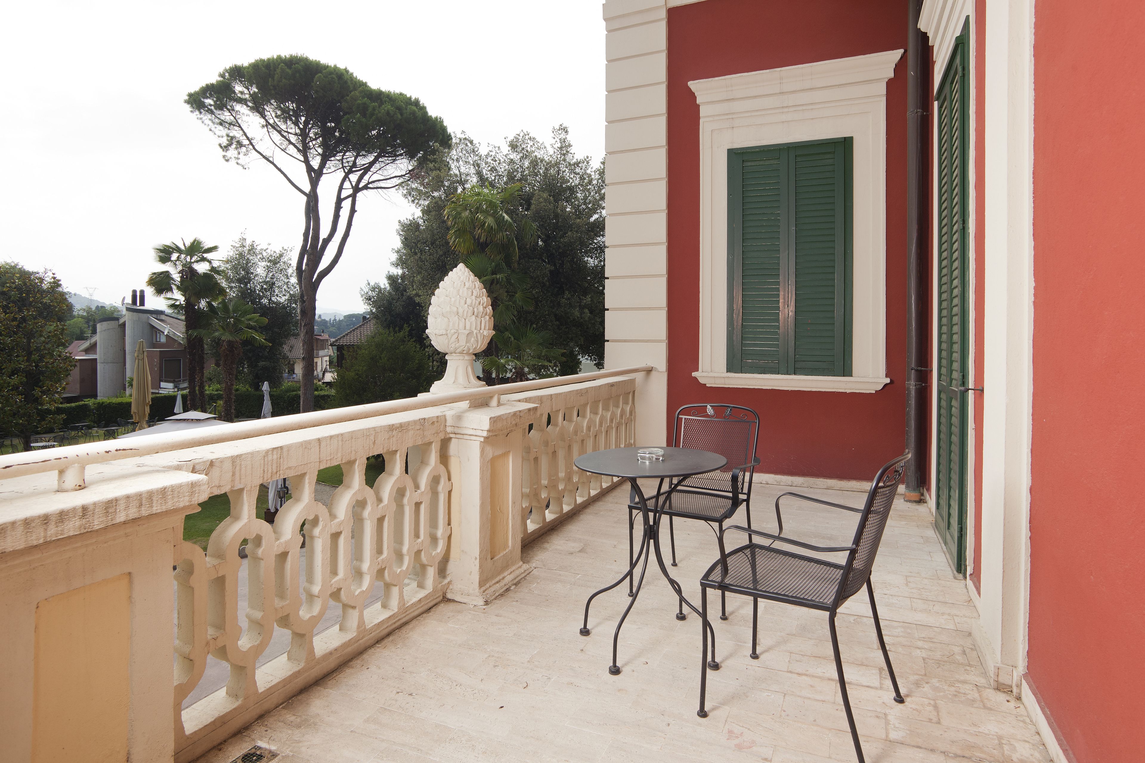 A balcony with a white balustrade, a table, and two chairs.