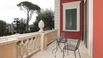 Ein Balkon mit weißer Brüstung, einem Tisch und zwei Stühlen.