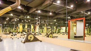 A gym with various exercise machines, mirrors, and a red-framed door. - Eastern Garden Service Apartment (Shanghai)
