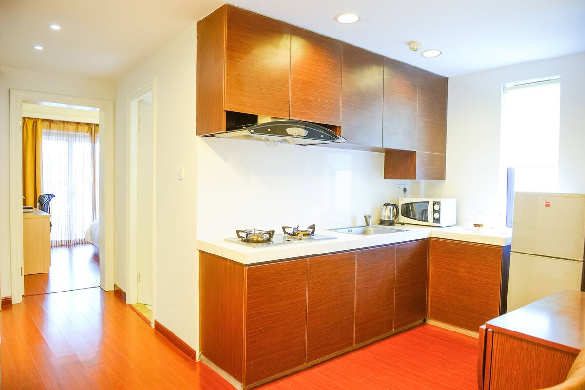 A compact kitchen with wooden cabinets, a microwave, and a sink.