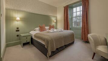 A bedroom with a bed, nightstands, a chair, a window with curtains, and wall-mounted lights.