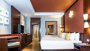Une chambre d’hôtel avec un grand lit, un bureau, une télévision et une salle de bain visible à travers une porte.