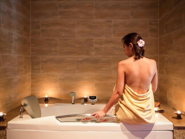 A person in a towel in a bathroom with a bathtub, a shower, and a mirror.