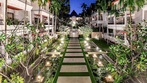 A well-lit pathway leading to a building with multiple balconies, surrounded by lush greenery and palm trees. - Beyond Samui (Koh Samui)
