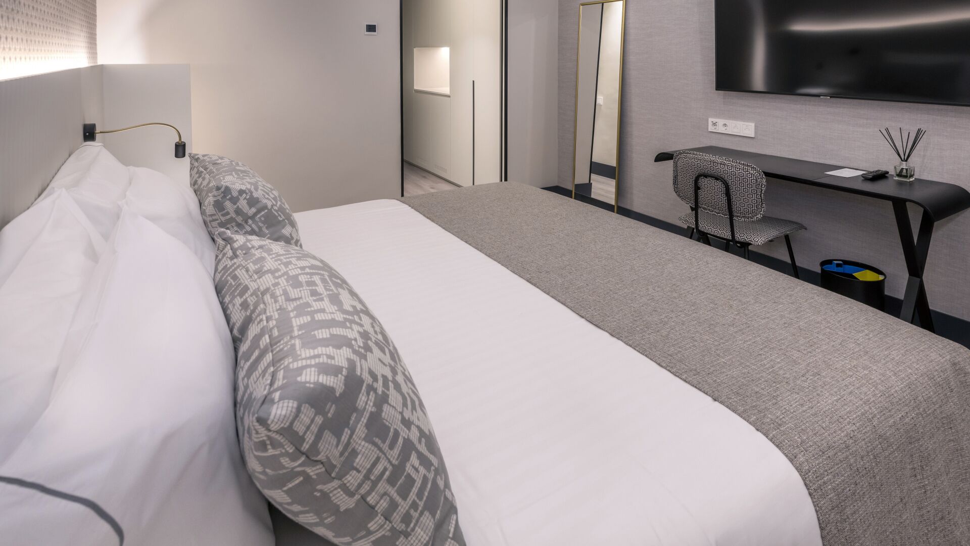 A hotel room with a bed, a desk, and a TV.