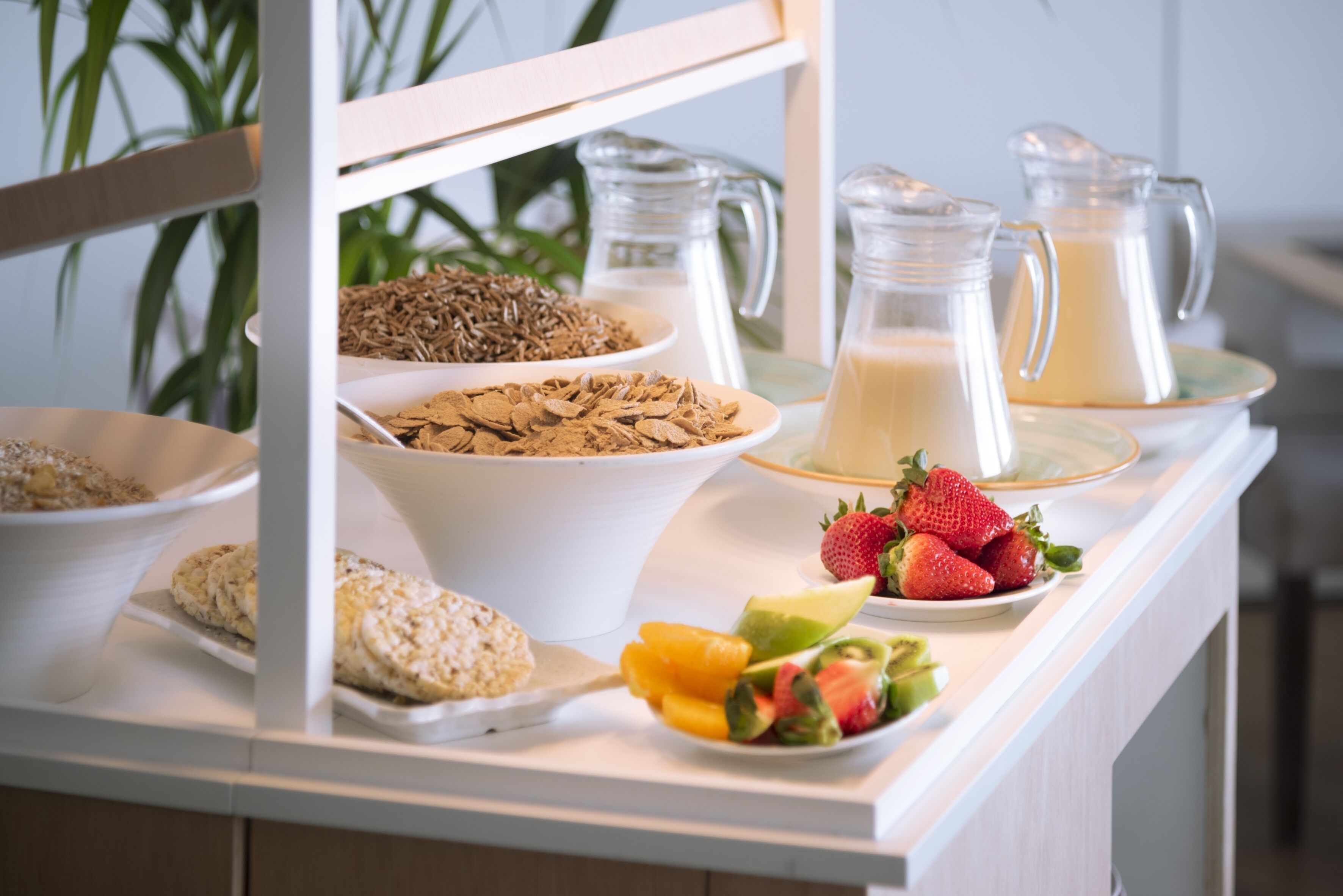 A buffet with various food items including cereals, milk, and fresh fruits.