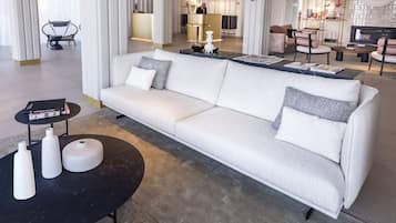 A modern hotel lobby with a white sofa, a round coffee table, and a reception desk.