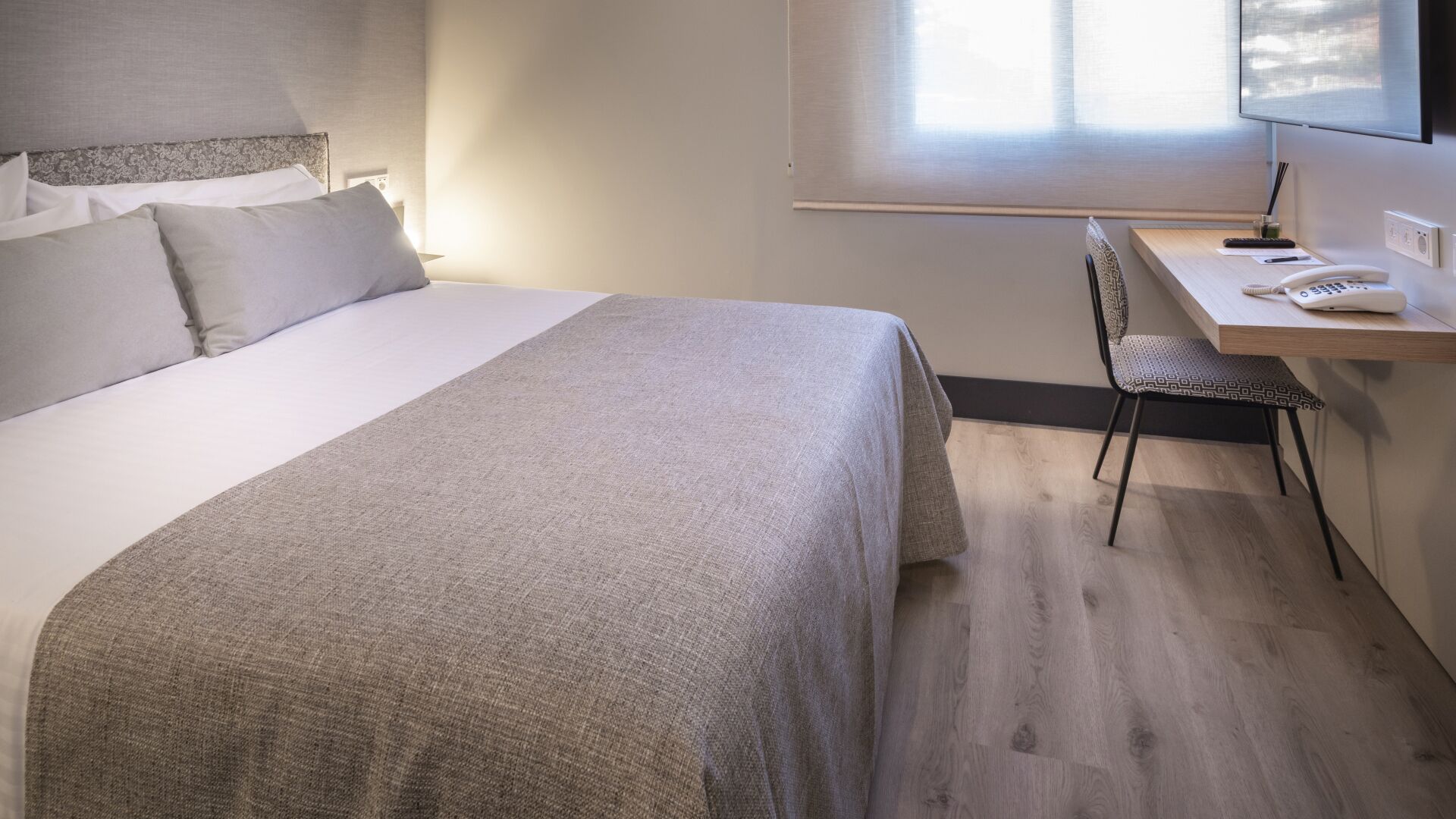 Una habitación de hotel con una cama, un escritorio y una silla.