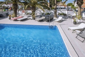 A swimming pool with lounge chairs and palm trees. - Bel Air Hotel (Castelldefels)