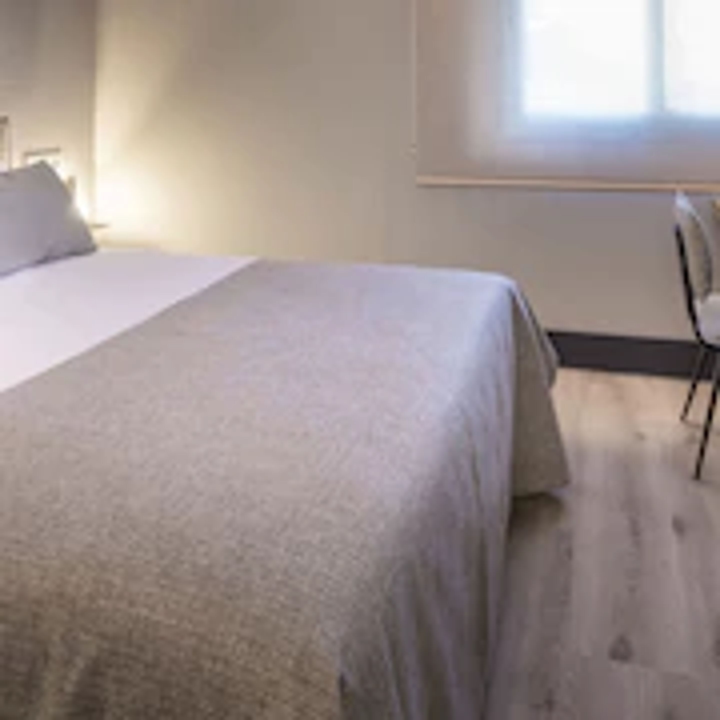 Ein Schlafzimmer mit Bett, Stuhl und Fenster.