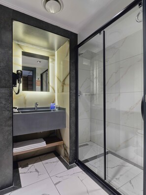A modern bathroom with a large mirror, a built-in sink, and a glass-enclosed shower. - Dedeman Sanliurfa (Sanliurfa)