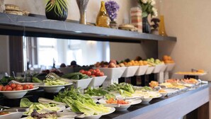 Un buffet proposant une variété de plats, notamment des salades, des fruits et des légumes.
