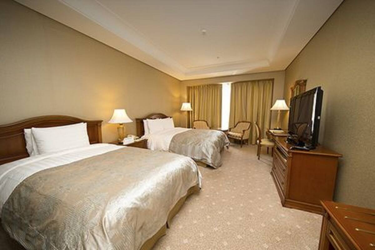 Ett hotellrum med två sängar, en tv, ett skrivbord och en stol.