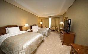 A hotel room with two beds, a television, a desk, and a chair.