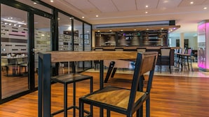 Un restaurante moderno con suelo de madera, sillas de metal negro y una larga mesa de madera.