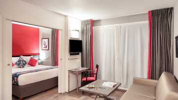 Una habitación de hotel con cama, escritorio, silla y sofá.